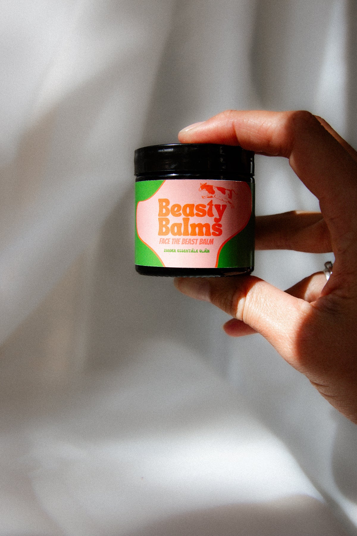 Hand holding a jar of Face the Beast grass-fed beef tallow face balm