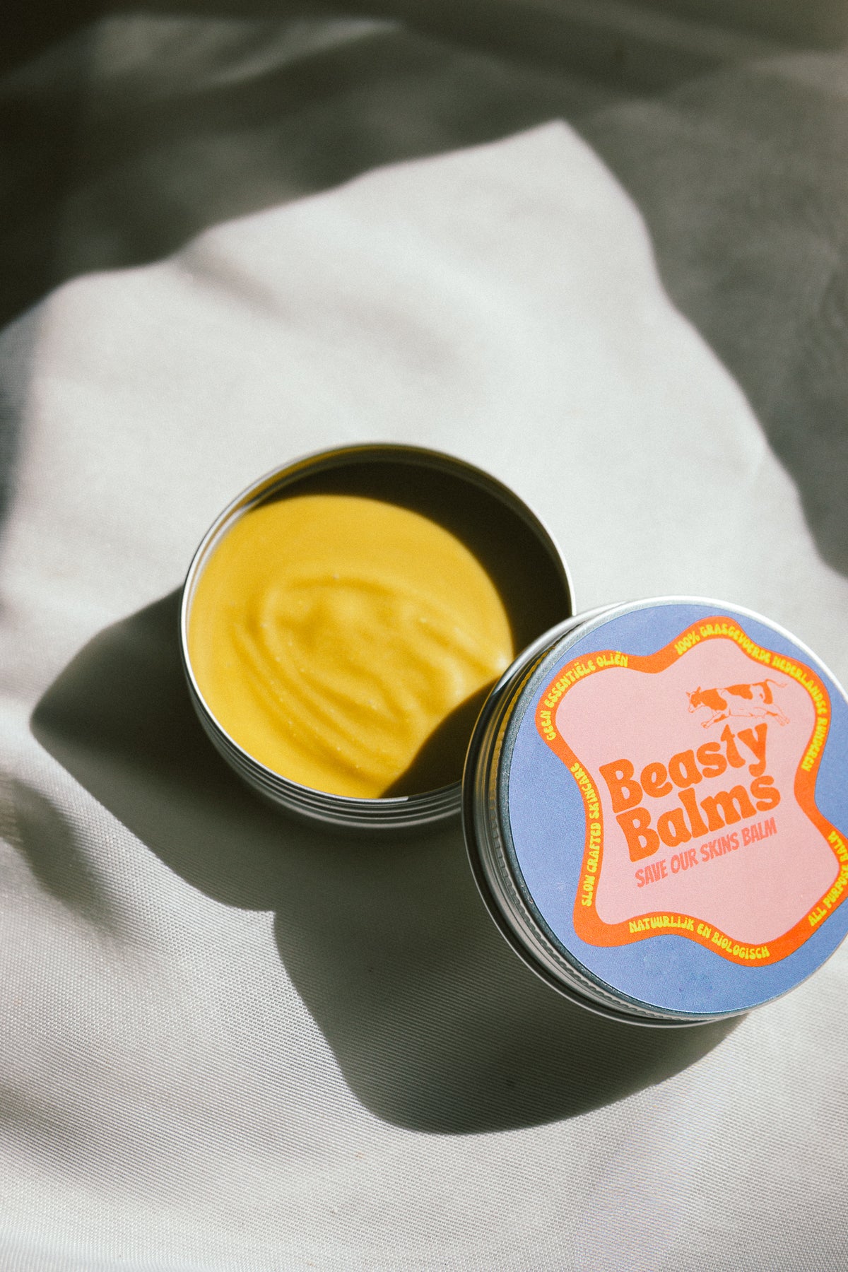 Open tin with lid next to it to show the texture of Save Our Skins grass-fed tallow balm